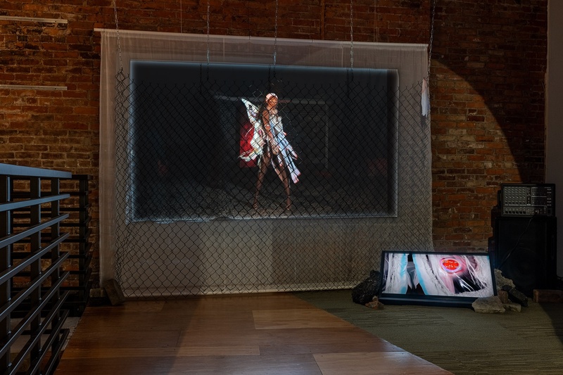  Still of the 2-channel video installation. One video has a model figure wearing an abstract outfit the other is distorted on the ground. 