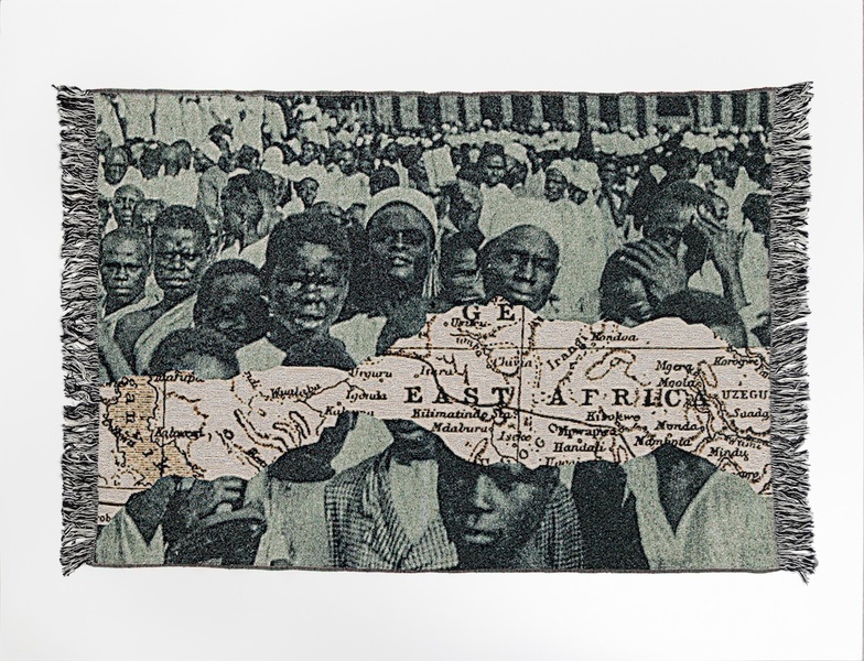  A photo of a textile hung on a white gallery wall. The textile is tinted green and depicts a large group of Black people standing and looking out. In the center is a portion of the map of Africa. 