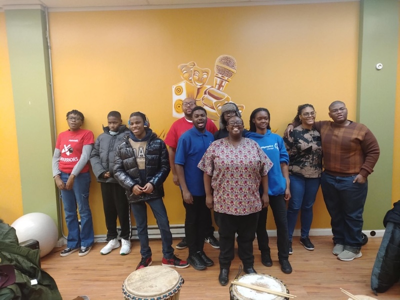  A group of people stand in front of a yellow wall and smile for the camera. 