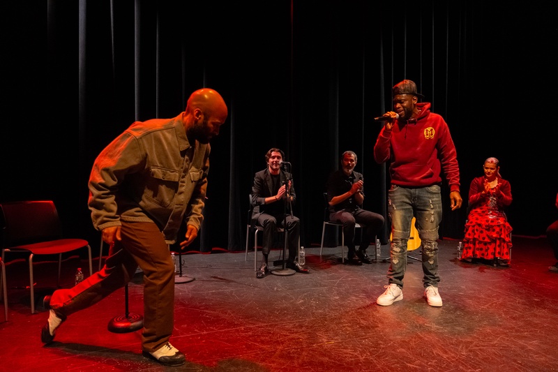  A dancer and a man with a microphone stand on stage about to begin a performance. 