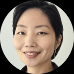 Headshot of a middle-aged East Asian woman with short hair, smiling and wearing a black button-down shirt.